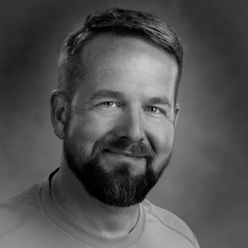 Black and white portrait of a man with a beard and a friendly smile.