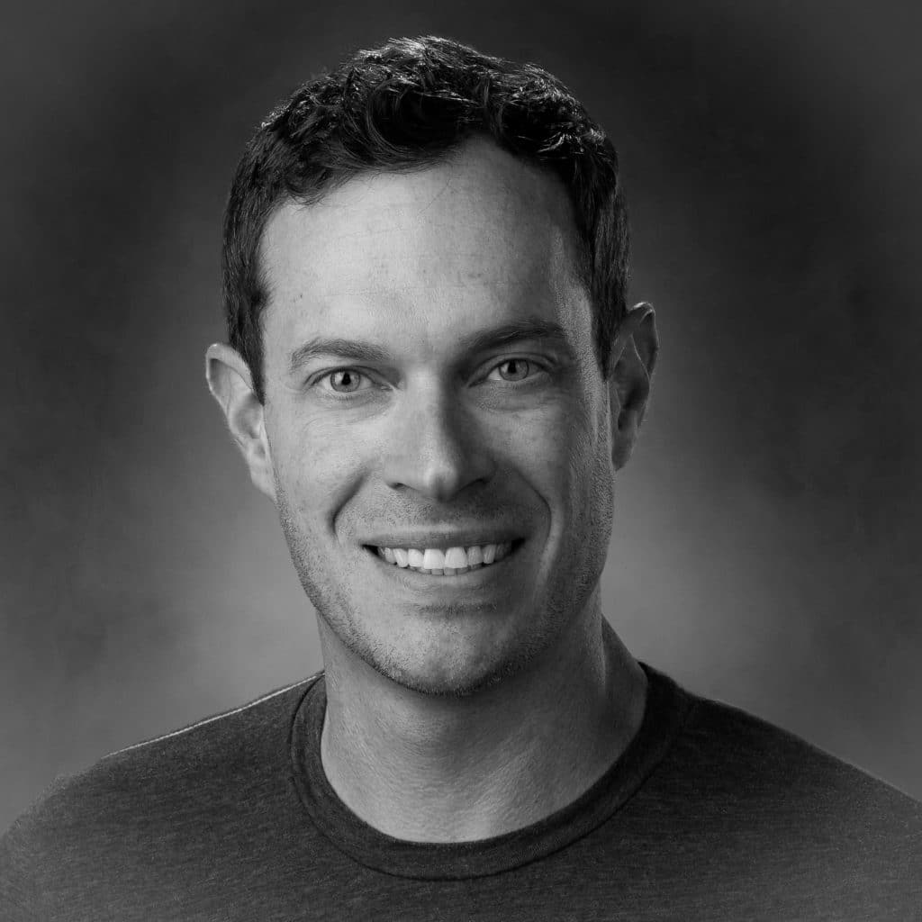 Black and white portrait of a man with short hair and a bright smile.