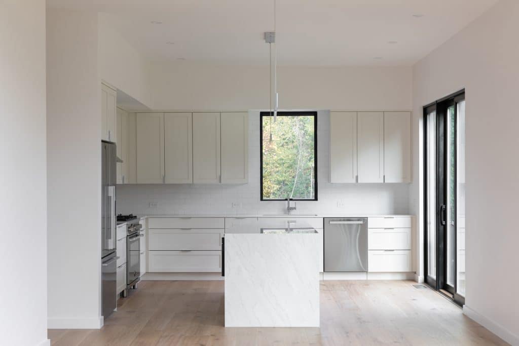 Modern kitchen near Hudson, NY with white cabinets, marble countertops, and stainless steel appliances.