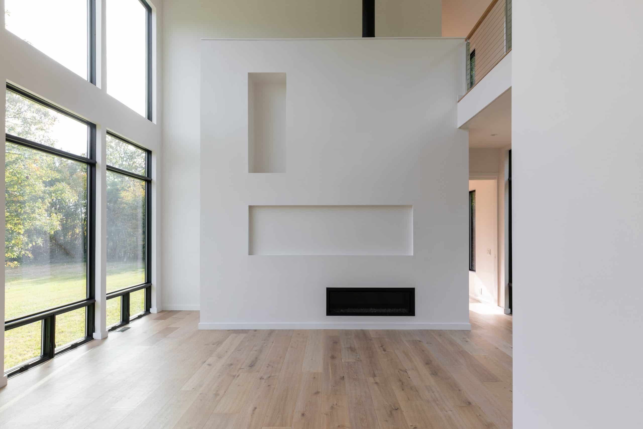 Living room in Hudson Valley with large windows, a modern fireplace, and built-in wall niches.