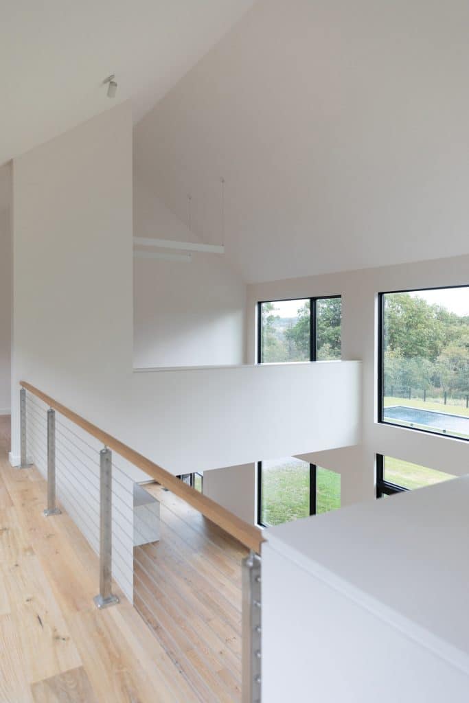 Open loft area in a modern custom home in Upstate New York with large windows and wooden floors.