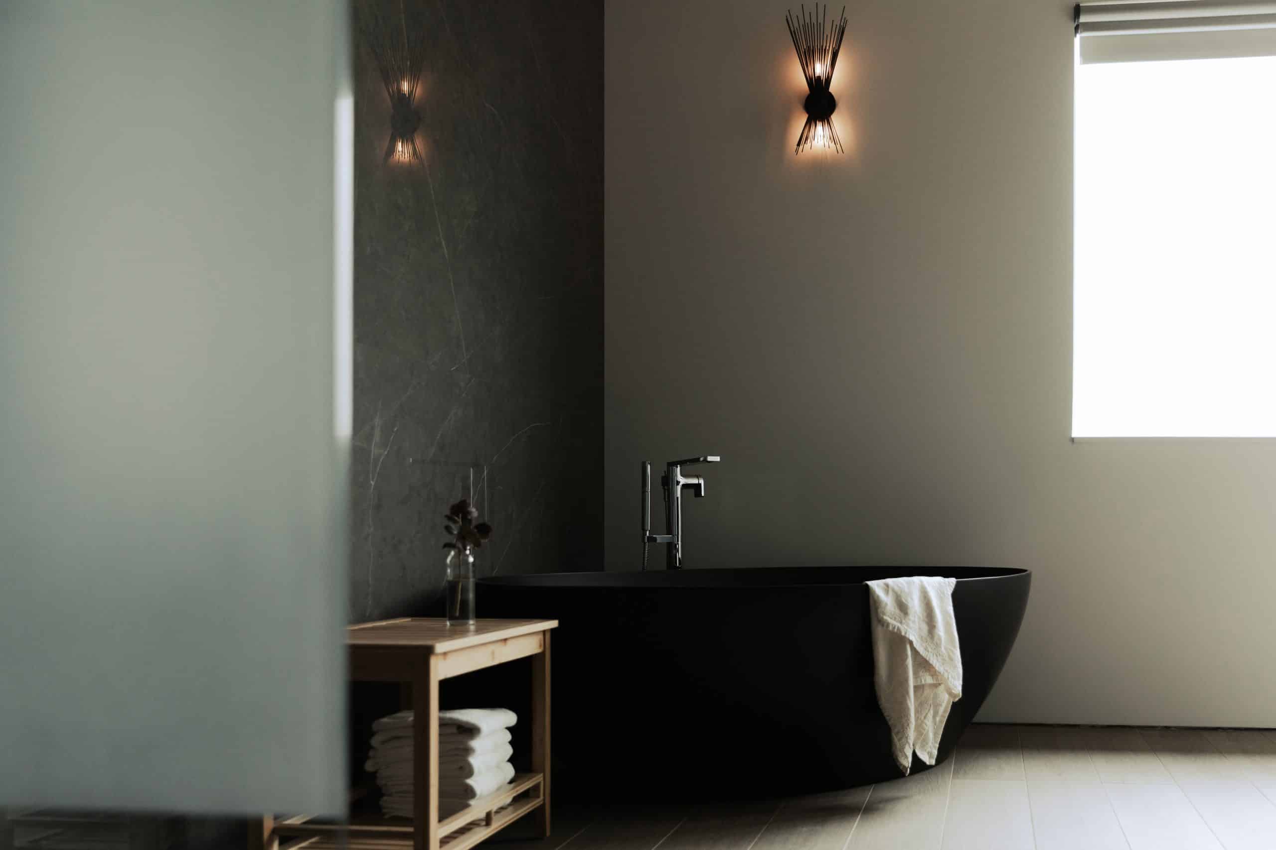 A sophisticated bathroom in a modern stone home in Chatham, NY, featuring black decor, contemporary fixtures, a walk-in shower with black hexagonal tiles, and sleek cabinetry.